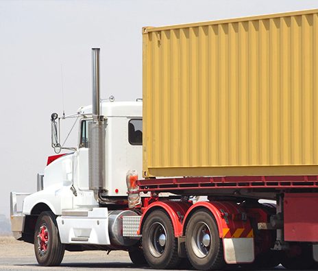 A semi truck with its trailer parked on the side of the road.