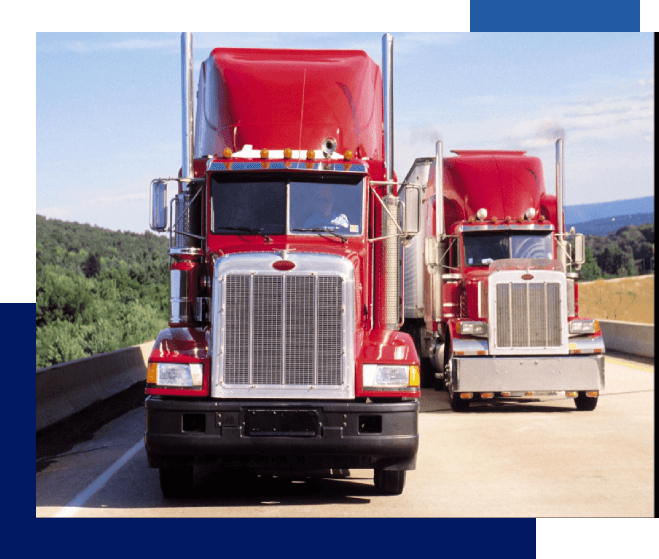 Two red trucks are driving down the road.