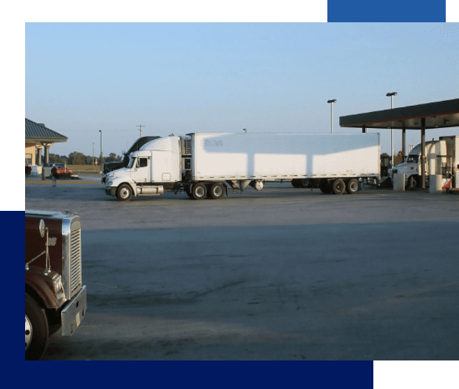 A truck is parked in the lot near a gas station.